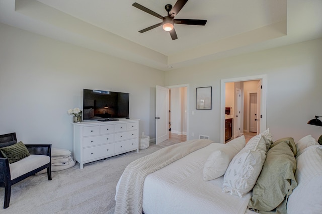 bedroom featuring light carpet, a raised ceiling, and a ceiling fan