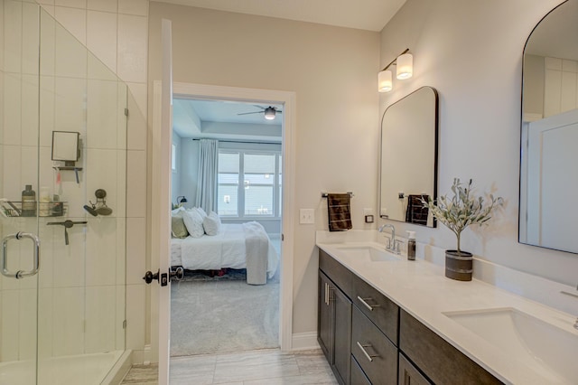 bathroom with ensuite bath, a stall shower, ceiling fan, double vanity, and baseboards