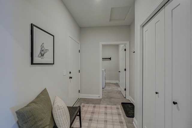 hall featuring attic access and baseboards
