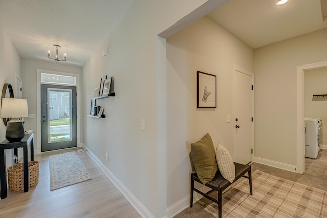 entrance foyer with a chandelier, baseboards, and light wood-style floors