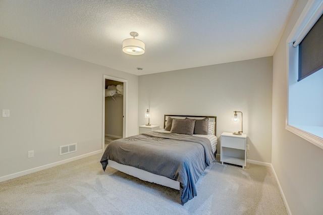 bedroom featuring carpet flooring, baseboards, a walk in closet, and a textured ceiling