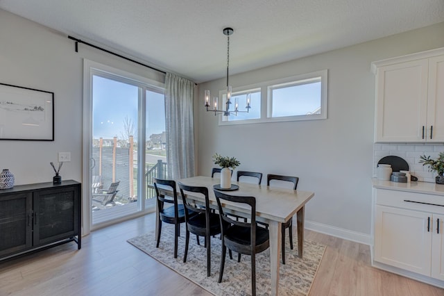 dining area featuring a chandelier, healthy amount of natural light, light wood-type flooring, and baseboards