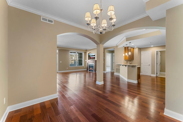 1320 Riverside Ln Unit 112, Mendota Heights, MN 55118 - unfurnished living room featuring arched walkways, dark wood-style floors, ornamental molding, a lit fireplace, and a chandelier