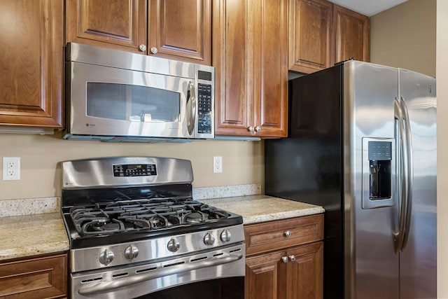 1320 Riverside Ln Unit 112, Mendota Heights, MN 55118 - kitchen with stainless steel appliances, brown cabinets, and light stone counters