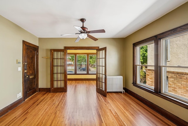 3441 Portland Ave Unit 1, Minneapolis, MN 55407 - unfurnished room featuring radiator, french doors, light wood finished floors, and baseboards