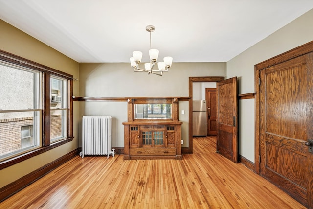 3441 Portland Ave Unit 1, Minneapolis, MN 55407 - unfurnished living room featuring radiator heating unit, a chandelier, light wood-type flooring, and baseboards