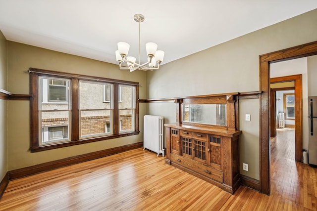 3441 Portland Ave Unit 1, Minneapolis, MN 55407 - dining space with radiator, a chandelier, light wood-type flooring, and baseboards