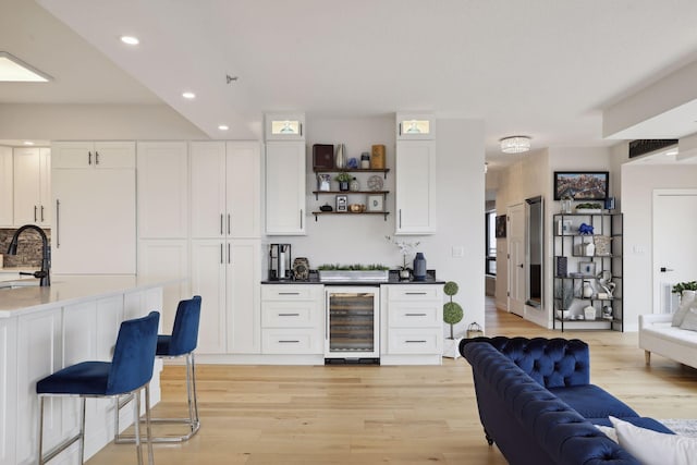 bar with wine cooler, a sink, recessed lighting, and light wood-style floors