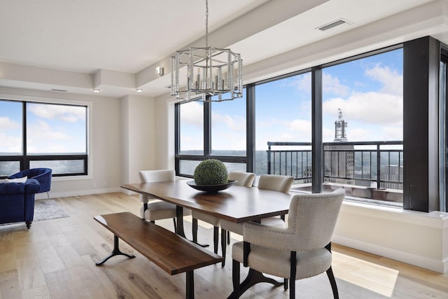dining area featuring a chandelier, baseboards, light wood finished floors, and plenty of natural light