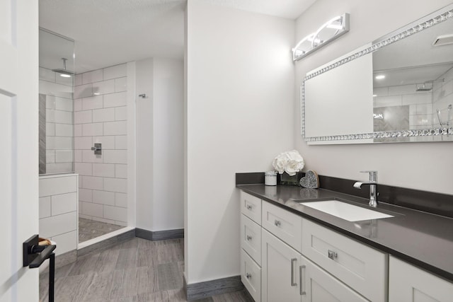 bathroom with walk in shower, vanity, baseboards, and wood finished floors