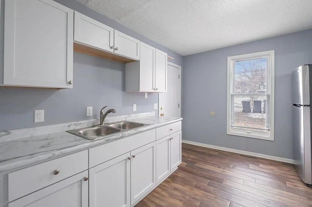 2723 Dupont Ave N, Minneapolis, MN 55411 - kitchen featuring freestanding refrigerator, a sink, dark wood-style floors, white cabinetry, and a textured ceiling