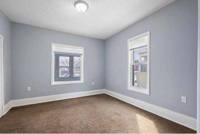 2723 Dupont Ave N, Minneapolis, MN 55411 - spare room featuring dark carpet, plenty of natural light, baseboards, and a textured ceiling
