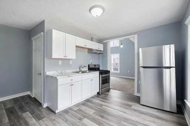 2723 Dupont Ave N, Minneapolis, MN 55411 - kitchen with stainless steel appliances, a sink, light wood-style flooring, white cabinetry, and baseboards