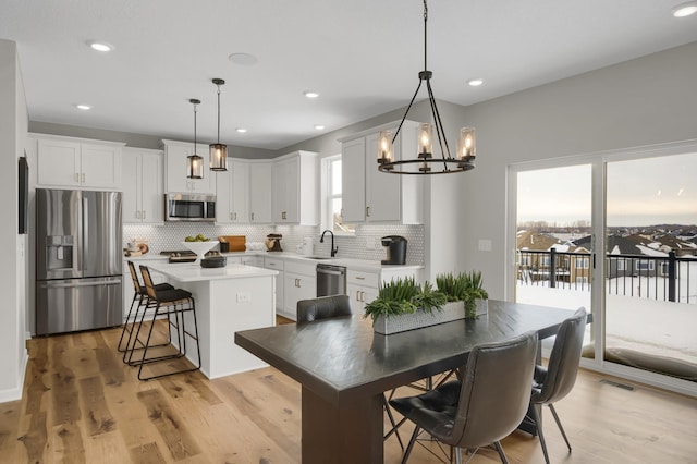 19307 Colonial Trl, Farmington, MN 55024 - kitchen with stainless steel appliances, a kitchen island, tasteful backsplash, light countertops, and a chandelier