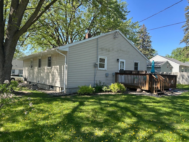 back of house featuring a deck, a chimney, and a yard