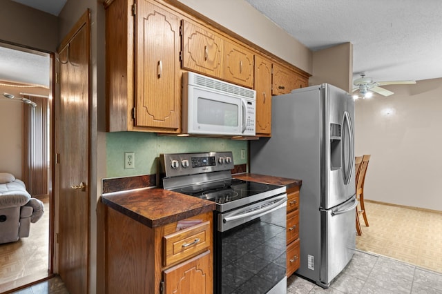8251 158th Ln NW, Ramsey, MN 55303 - kitchen featuring stainless steel appliances, dark countertops, ceiling fan, a textured ceiling, and brown cabinets