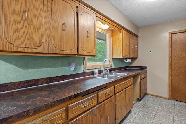 8251 158th Ln NW, Ramsey, MN 55303 - kitchen with a sink, dark countertops, a textured ceiling, brown cabinetry, and baseboards