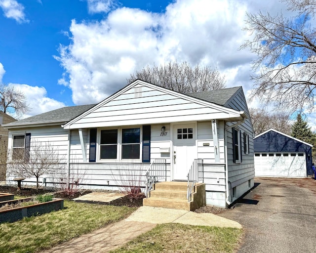view of front facade featuring a garage, roof with shingles, and an outdoor structure