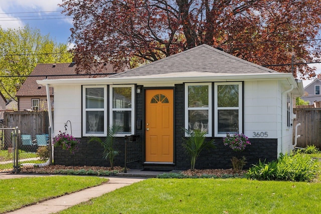 bungalow-style home featuring a shingled roof and a gate