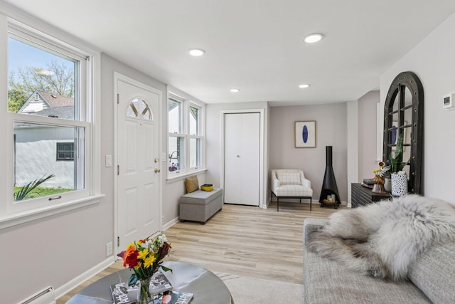 living area featuring baseboard heating, recessed lighting, light wood-style floors, and baseboards