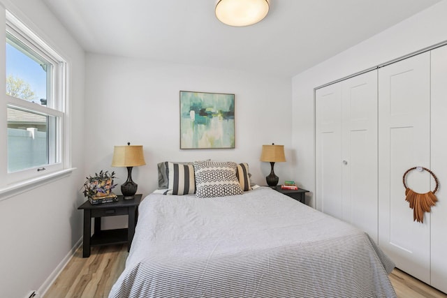 bedroom with light wood finished floors, a closet, and baseboards