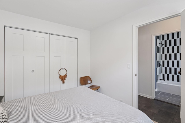 bedroom featuring dark tile patterned flooring, a closet, and baseboards
