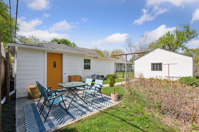 rear view of house with roof with shingles, a patio, and outdoor dining area
