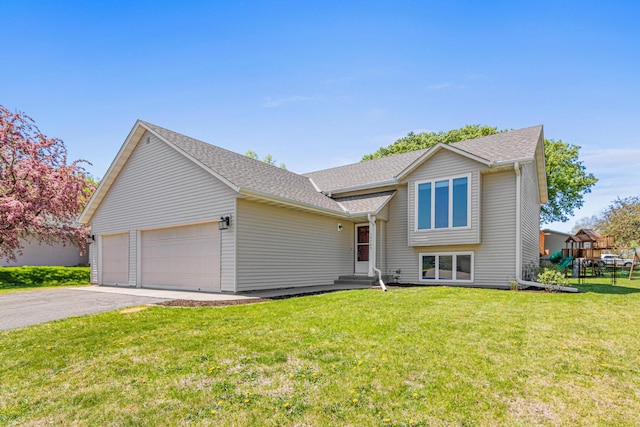 split level home with an attached garage, a front yard, driveway, and a shingled roof
