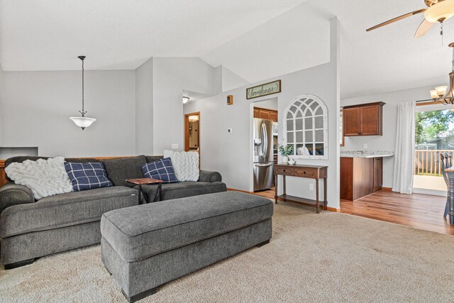 living area with vaulted ceiling, light carpet, a ceiling fan, a chandelier, and baseboards