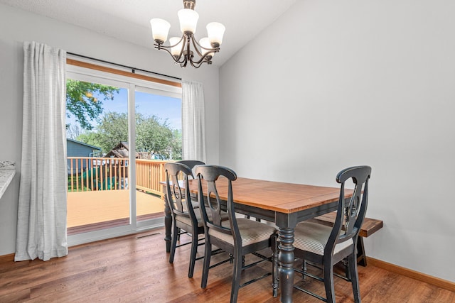 dining room with a chandelier, wood finished floors, vaulted ceiling, and baseboards