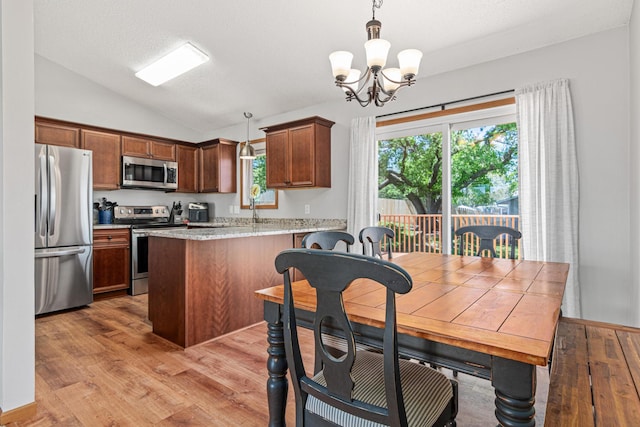 kitchen with appliances with stainless steel finishes, lofted ceiling, a chandelier, light wood-style floors, and a peninsula
