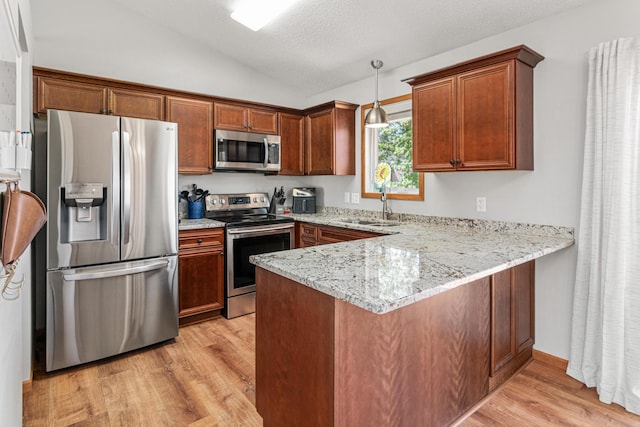 kitchen with stainless steel appliances, light wood-style flooring, a peninsula, lofted ceiling, and a sink