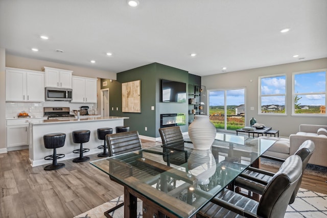 22654 Isla Way, Rogers, MN 55374 - dining room with recessed lighting, light wood-style flooring, baseboards, and a glass covered fireplace