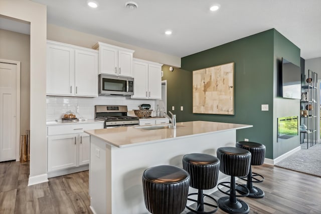 22654 Isla Way, Rogers, MN 55374 - kitchen featuring appliances with stainless steel finishes, a sink, wood finished floors, white cabinetry, and light countertops