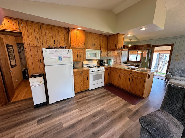 43084 335th Ave, Dora Twp, MN 56528 - kitchen featuring white appliances, a sink, brown cabinetry, lofted ceiling, and wood walls
