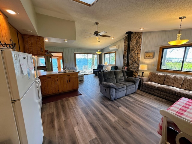 43084 335th Ave, Dora Twp, MN 56528 - living room with a wood stove, wood walls, vaulted ceiling, dark wood finished floors, and a textured ceiling
