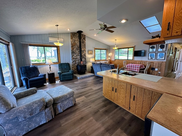 43084 335th Ave, Dora Twp, MN 56528 - living area featuring a wood stove, lofted ceiling, dark wood finished floors, ceiling fan, and wooden walls