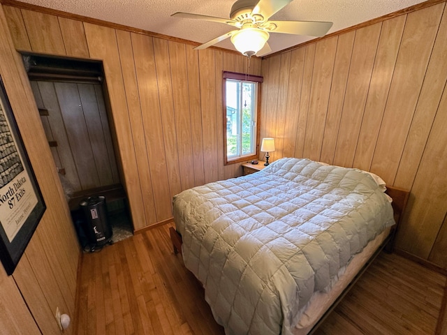43084 335th Ave, Dora Twp, MN 56528 - bedroom with wood-type flooring, wood walls, a textured ceiling, a ceiling fan, and ornamental molding