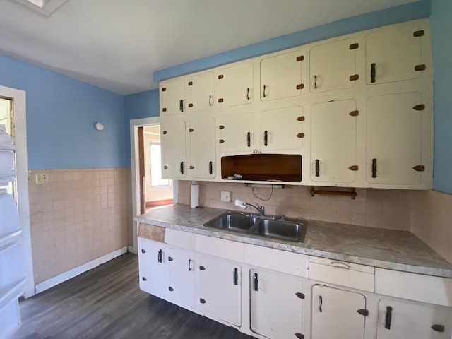 kitchen with a sink, dark wood finished floors, tile walls, wainscoting, and stainless steel counters