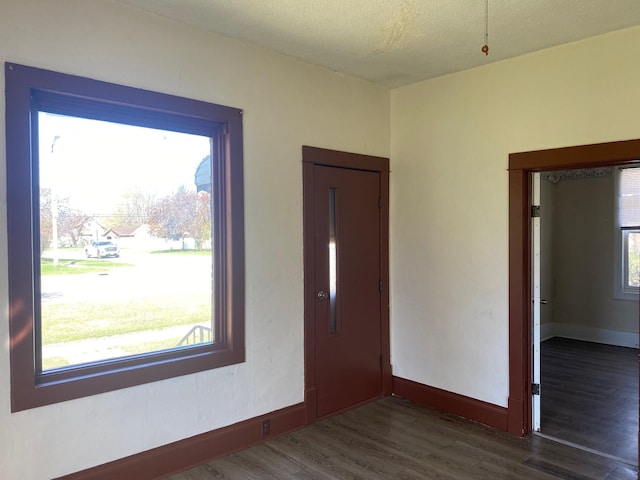 empty room featuring dark wood-type flooring, baseboards, and a textured ceiling