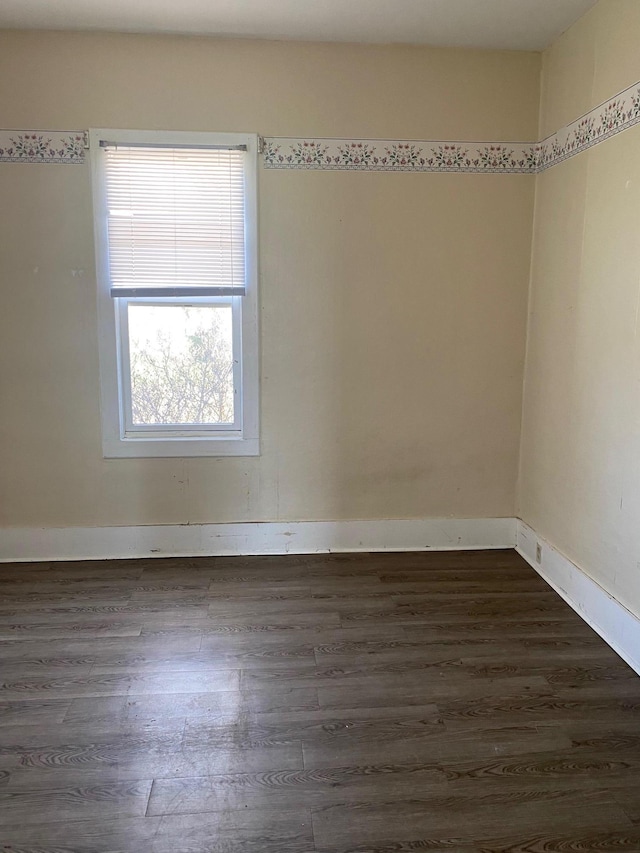 spare room featuring dark wood-type flooring and baseboards