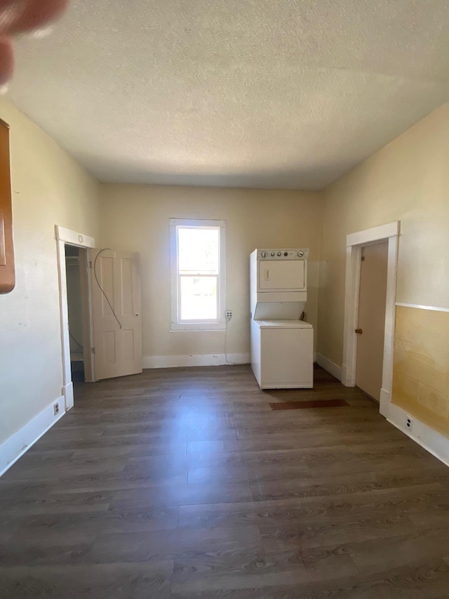 laundry room with estacked washer and dryer, dark wood-style flooring, baseboards, and a textured ceiling