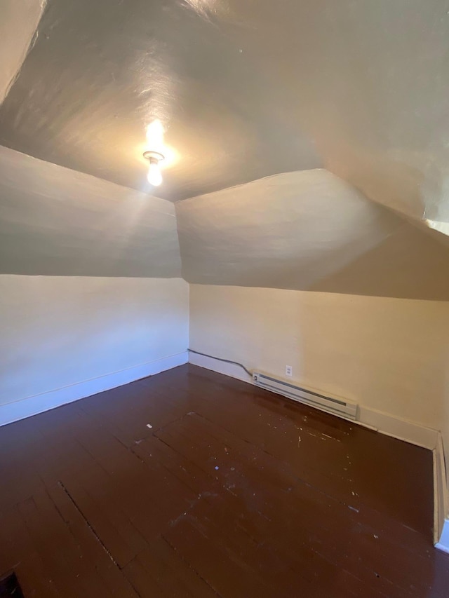 additional living space featuring baseboard heating, hardwood / wood-style flooring, vaulted ceiling, and baseboards