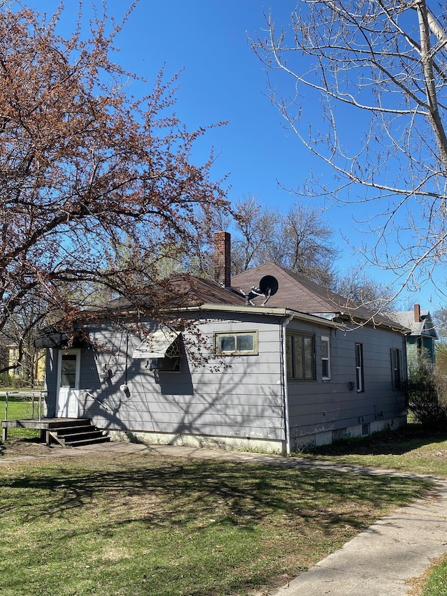 view of property exterior with a chimney and a yard