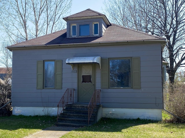 bungalow featuring roof with shingles and a front yard