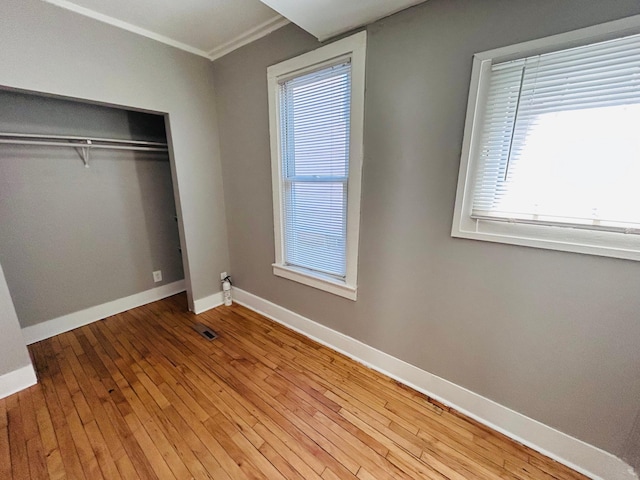 852 4th St E, Saint Paul, MN 55106 - unfurnished bedroom with baseboards, wood-type flooring, a closet, and ornamental molding