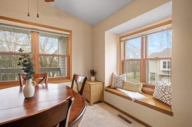 dining area featuring light colored carpet, vaulted ceiling, and baseboards