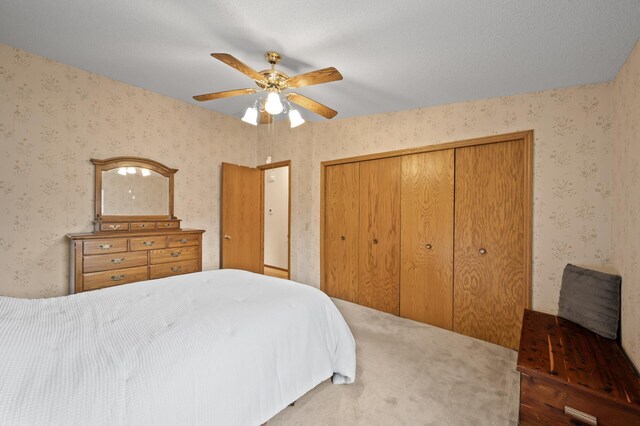 bedroom with a closet, wallpapered walls, and ceiling fan