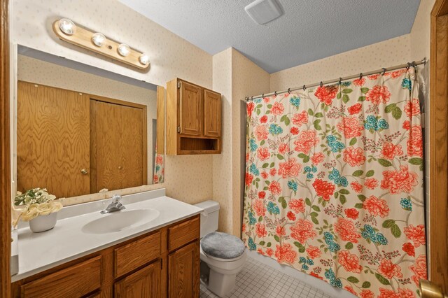 bathroom featuring wallpapered walls, toilet, a shower with shower curtain, tile patterned flooring, and a textured ceiling