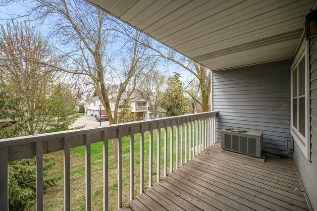 wooden terrace featuring central AC unit, a lawn, and a residential view